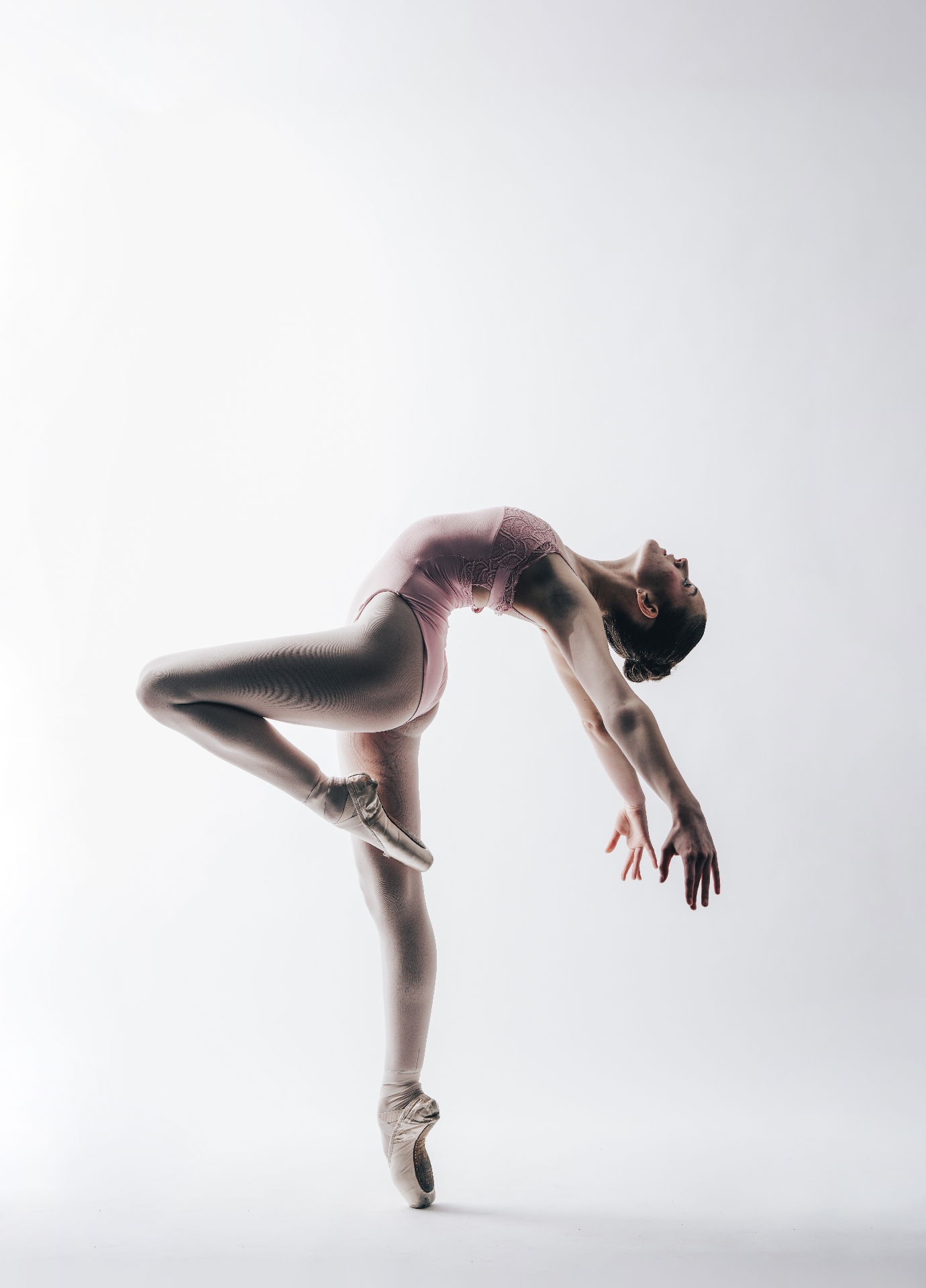 Ballet dancer in pink tutu performing an arabesque